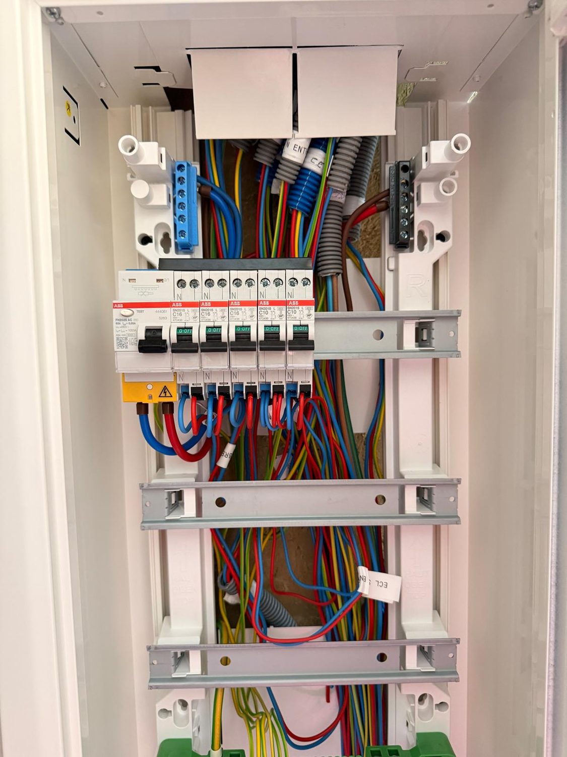 Armoire électrique ouverte au câblage soigné, protections modulaires et bornier de terre, chantier LB Électricité en Côtes-d'Armor